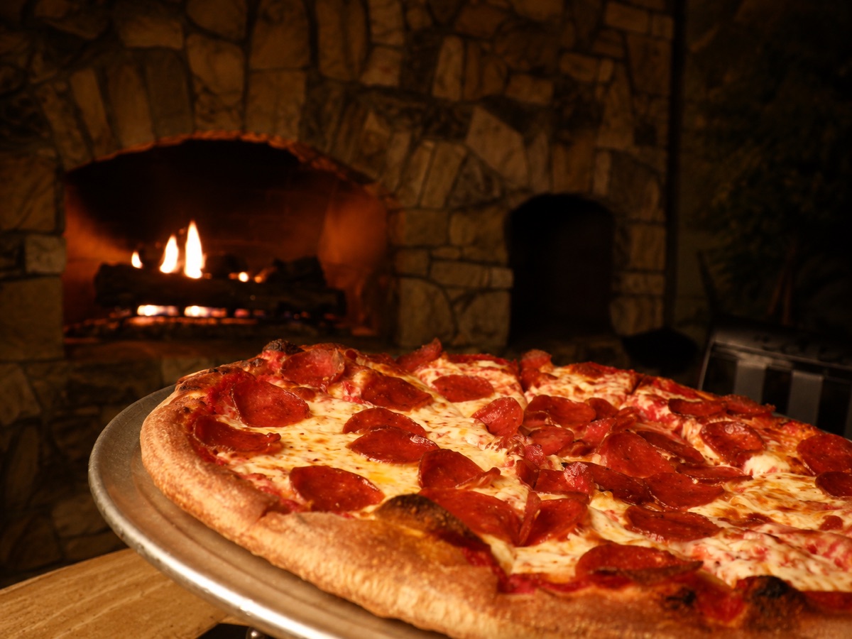 A pepperoni pizza in front of the stone fireplace